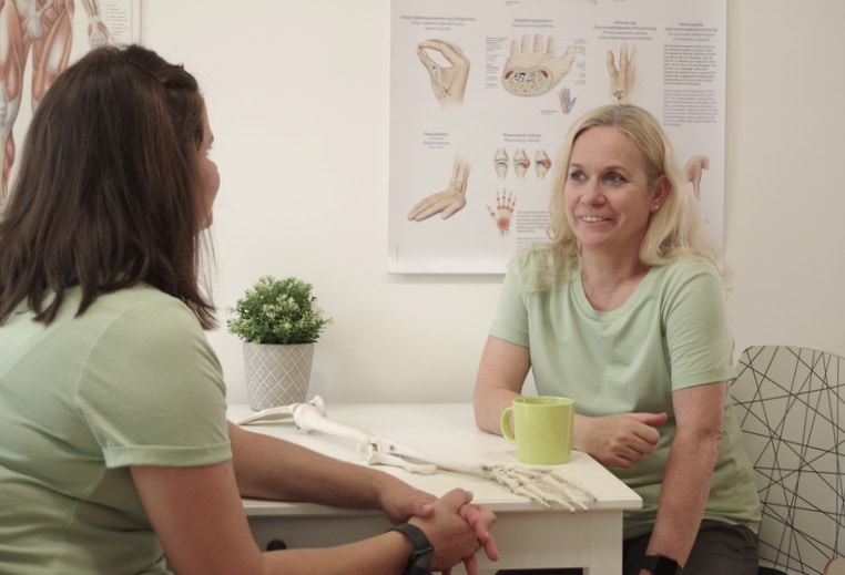Elena und Iris im Gespräch am Tisch – kollegialer Austausch in der Ergotherapiepraxis SENSUS